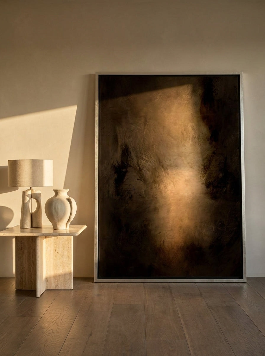 Oversized statement canvas wall art with a silver leaf surround leaning against the wall in a luxe dining room