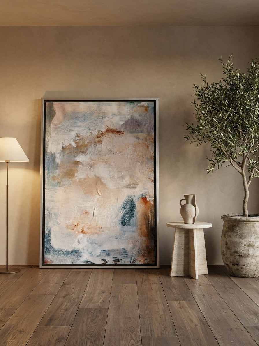 Oversized statement canvas wall art with a silver leaf surround leaning against the wall in a luxe dining room