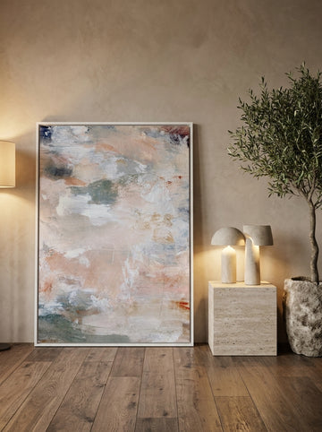 Oversized statement canvas wall art with a white surround leaning against the wall in a luxe dining room