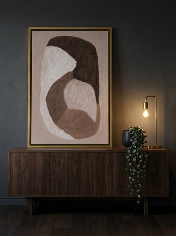Canvas wall art with a gold leaf surround standing on a sideboard in a moody bedroom