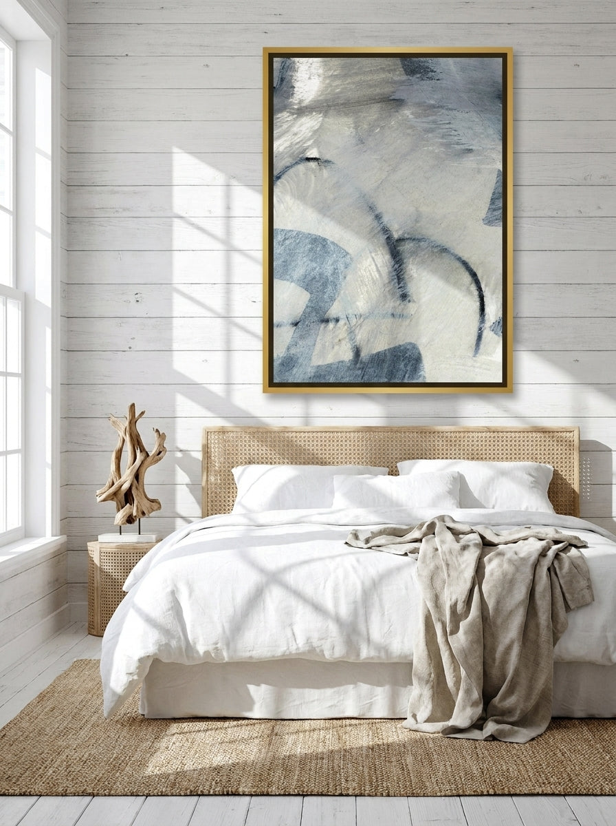 Canvas wall art with a gold leaf surround styled on the wall in a coastal bedroom