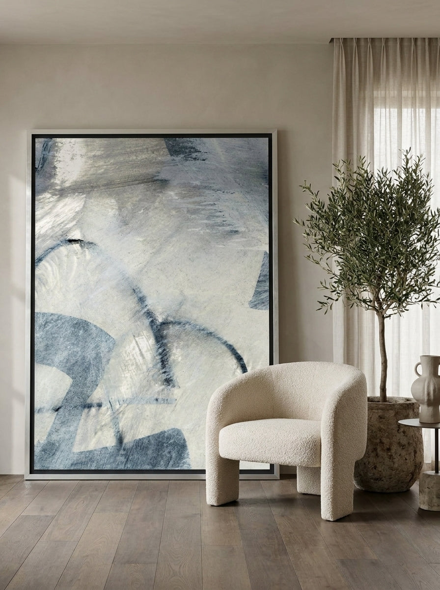 Oversized statement canvas wall art with a silver leaf surround leaning against the wall in a luxe dining room