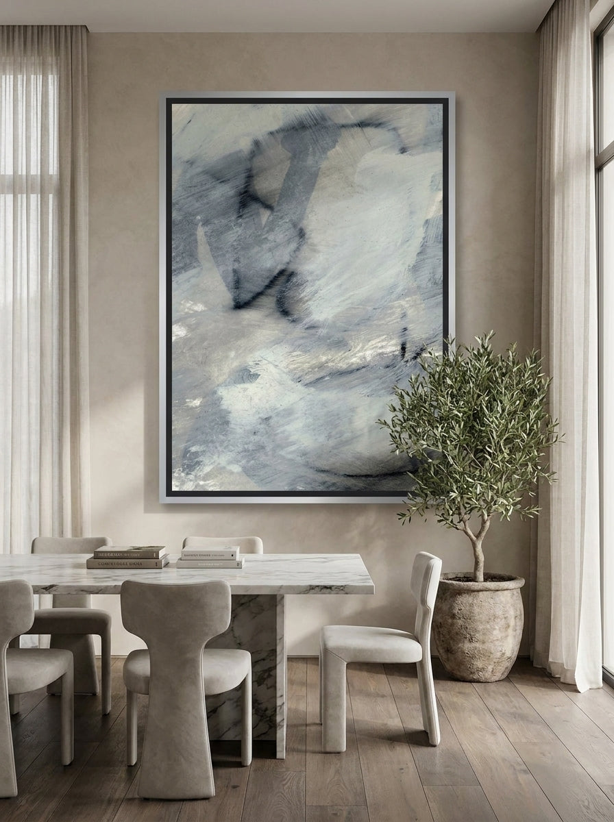 Oversized statement canvas wall art with a silver leaf surround styled on the wall in a luxe dining room