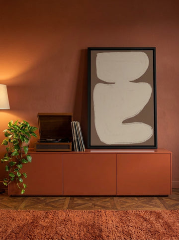 Canvas wall art with a black surround standing on a sideboard in a retro 70s living room