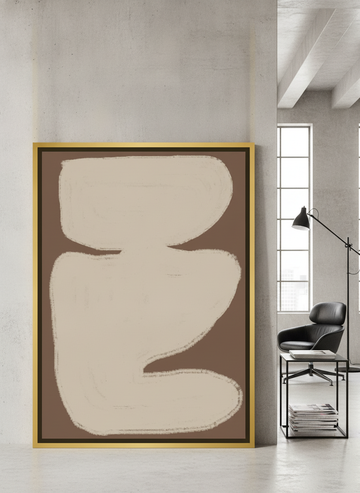 Canvas wall art with a gold leaf surround leaning against the wall in an industrial loft home office