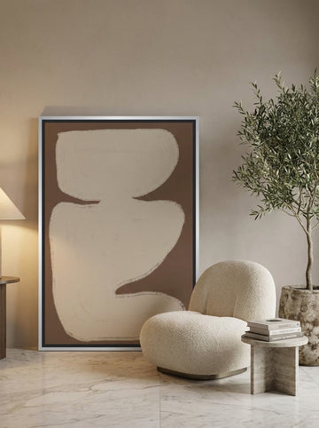 Oversized statement canvas wall art with a silver leaf surround leaning against the wall in a luxe bedroom
