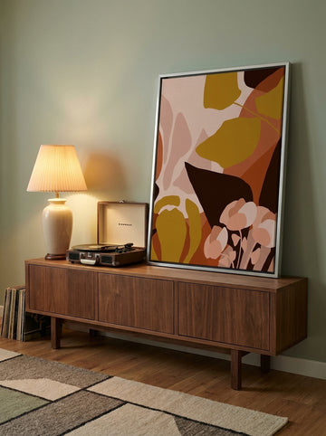 Canvas wall art with a silver leaf surround standing on a sideboard in a mid-century home office
