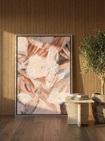 Oversized statement canvas wall art with a silver leaf surround leaning against the wall in a luxe living room