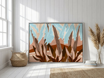 Oversized statement canvas wall art with a silver leaf surround leaning against the wall in a coastal dining room