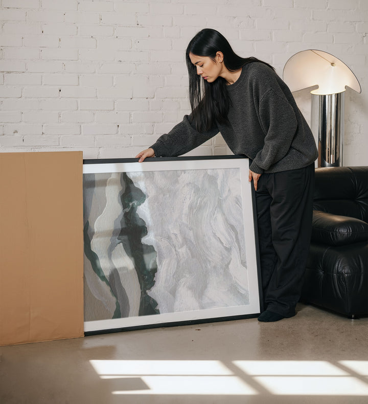 Woman holding an artwork in a modern living room.