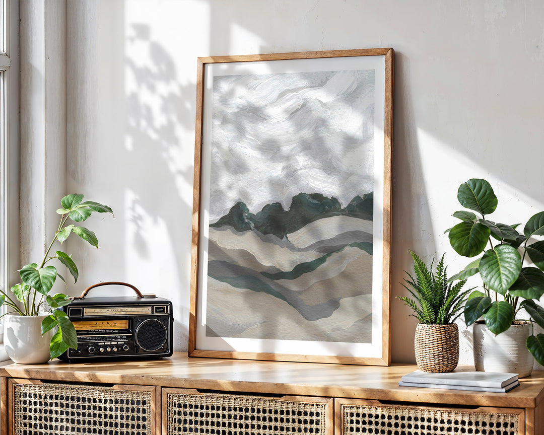 mountain landscape print on a wooden sideboard with plants and a radio.