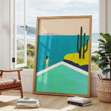 Artwork of a beach scene with a woman and cacti in a modern living room.