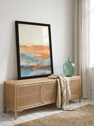 Modern wall art print standing on a sideboard in a coastal bedroom