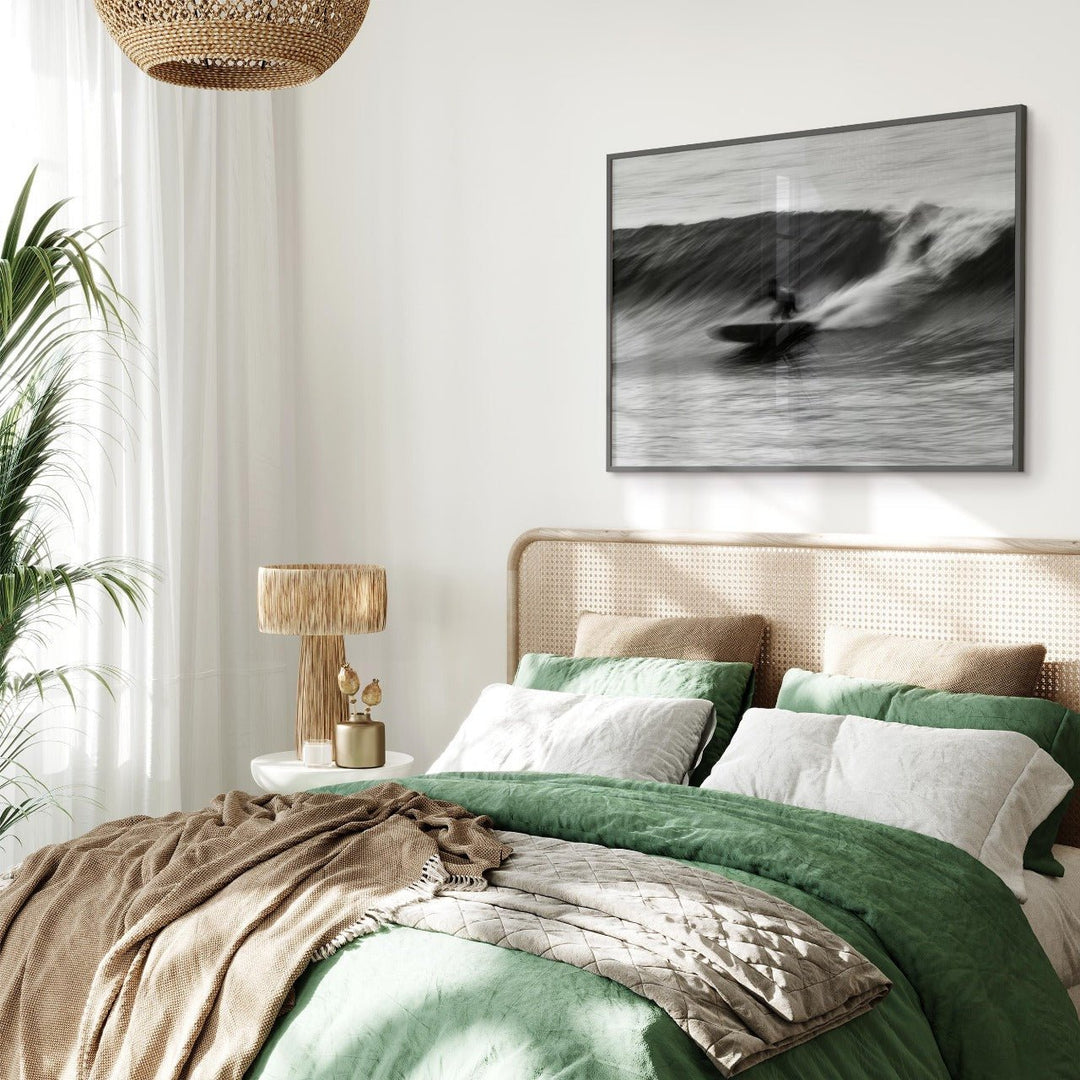Bedroom with green bedding, beige pillows, and an artwork on the wall.