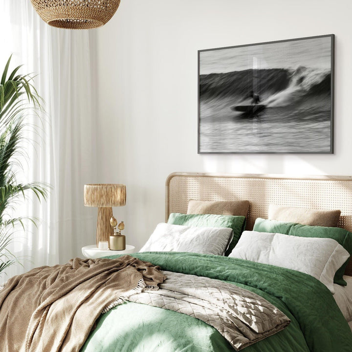Bedroom with green bedding, beige pillows, and an artwork on the wall.