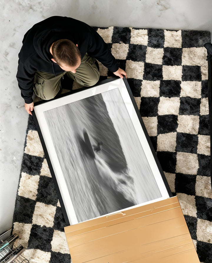 Person handling a black and white photograph on a checkered rug