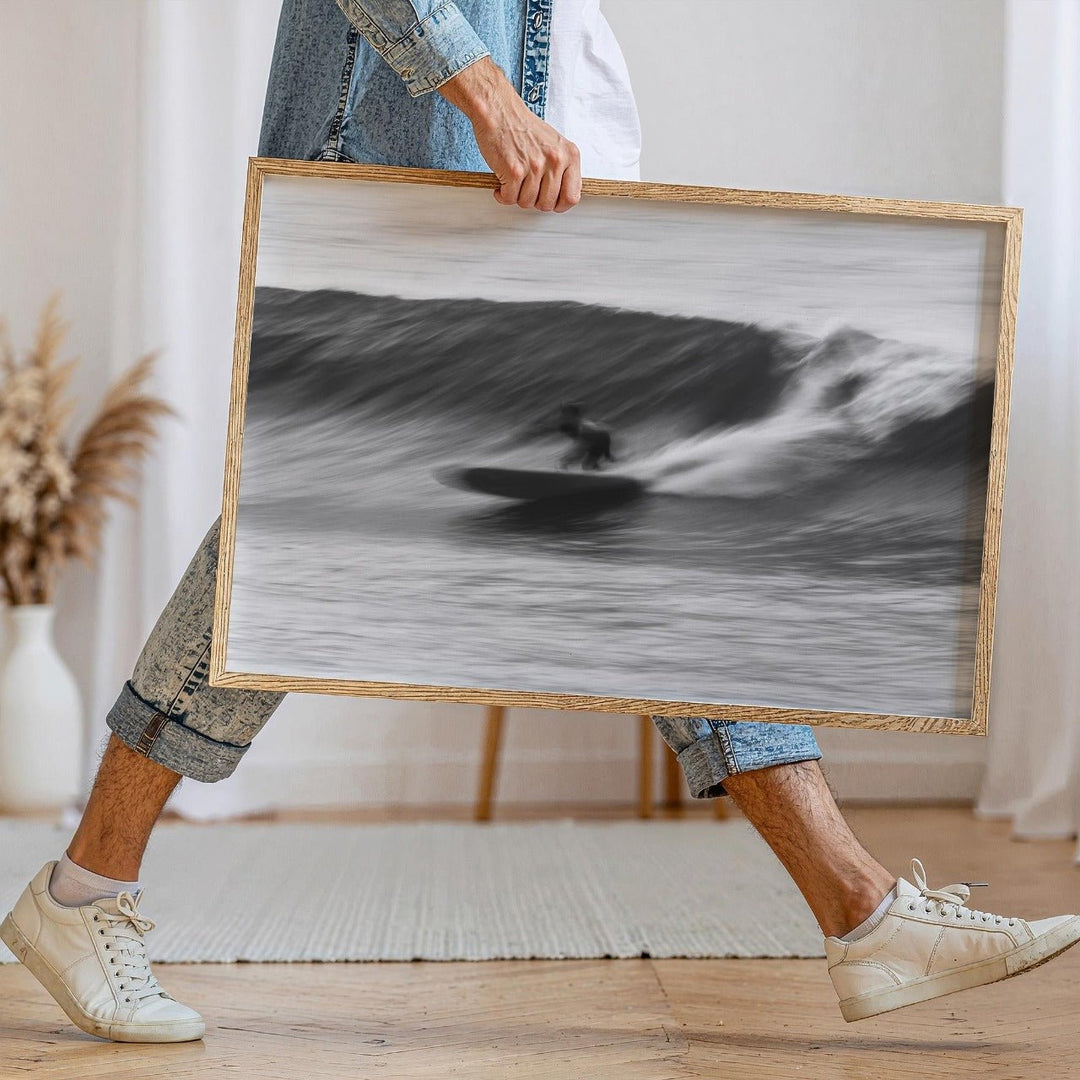 Person holding a black and white photograph of a surfer on a wave.