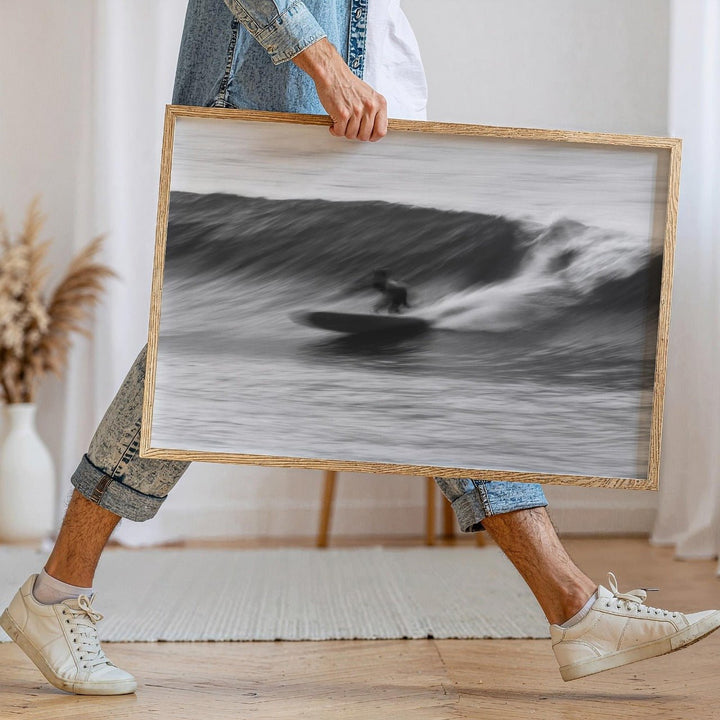 Person holding a black and white photograph of a surfer on a wave.