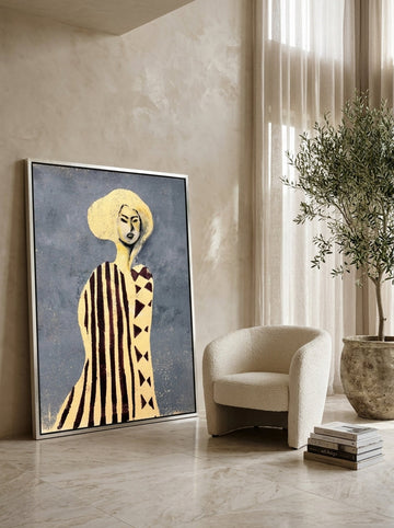 Oversized statement canvas wall art with a silver leaf surround leaning against the wall in a luxe dining room
