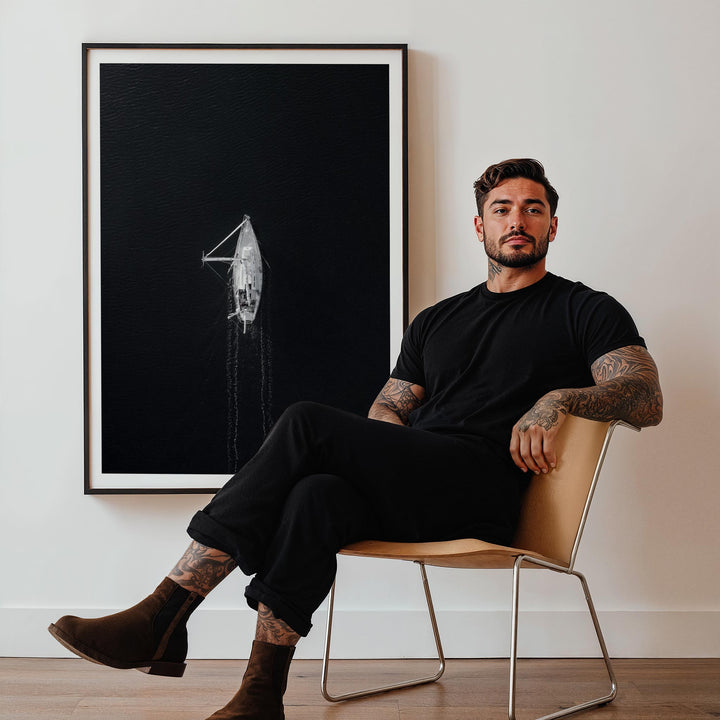Man sitting on a chair in a room with a large artwork on the wall.
