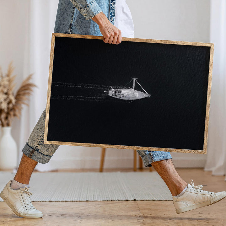 Person holding a black and white photograph of a boat on a wooden floor.