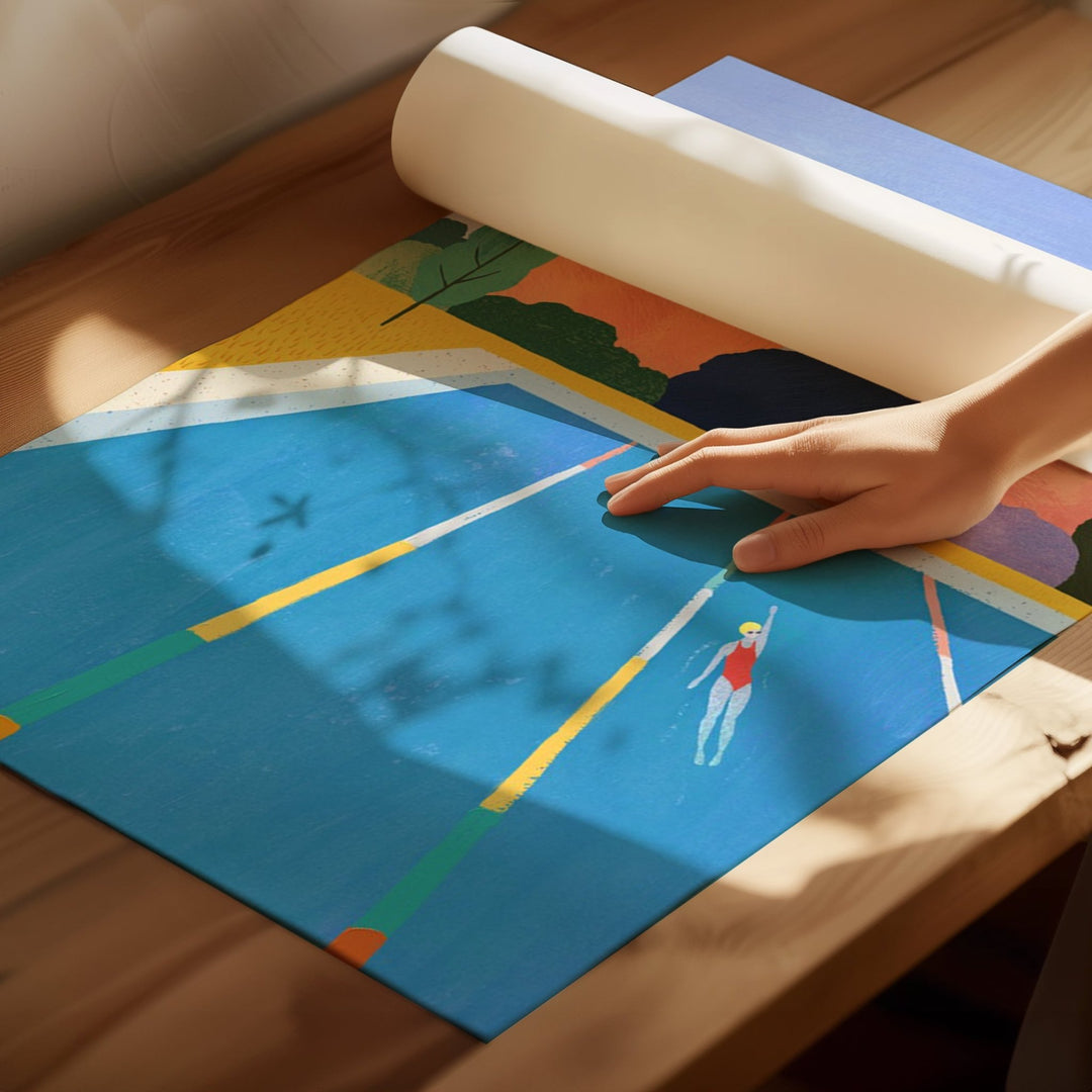 Colorful artwork with a design of a person swimming in a pool, being rolled out on a wooden floor.