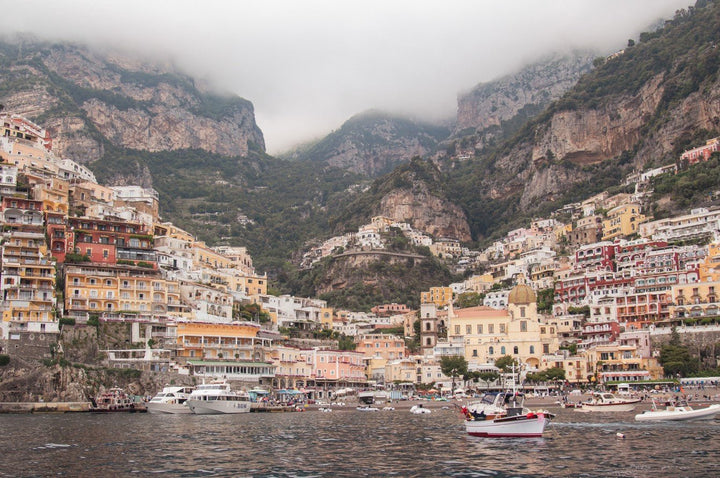 Hilly coastal town with colorful buildings and boats in the water framed