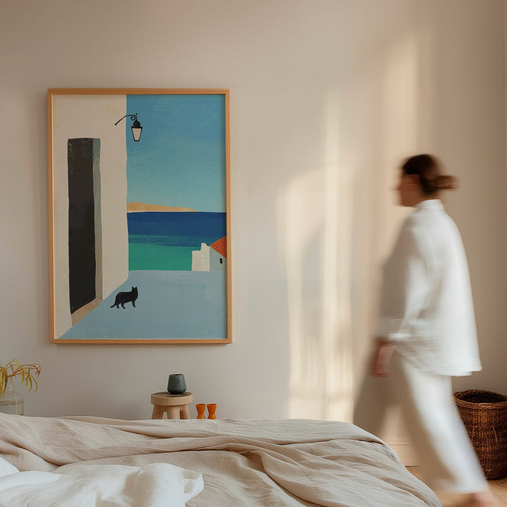 Woman walking past a painting of a coastal scene with a cat on a wall in a room.