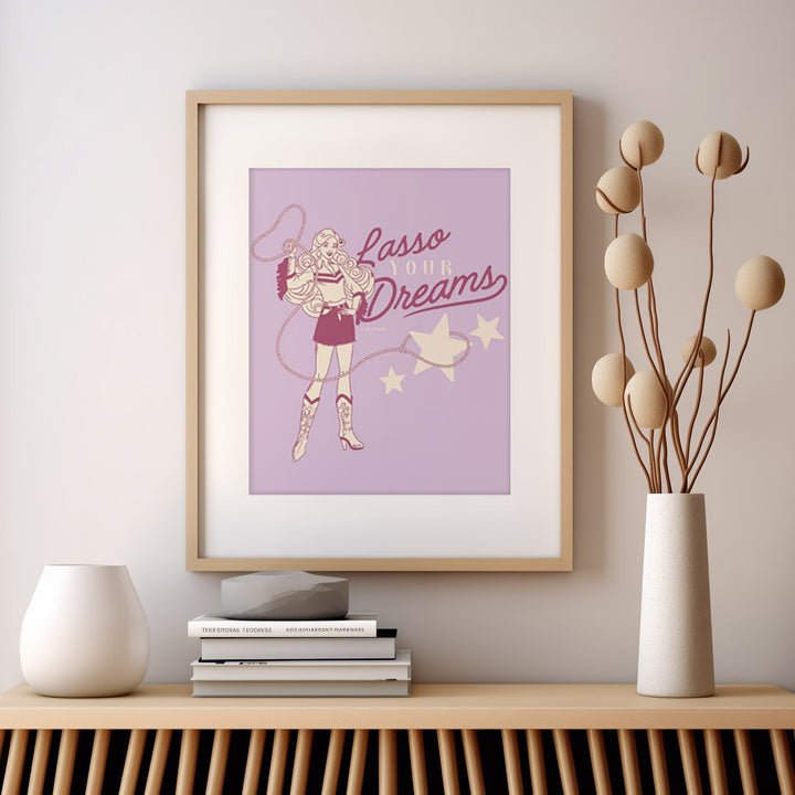 artwork with a character and 'Lasso Your Dreams' text on a wall above a wooden shelf.