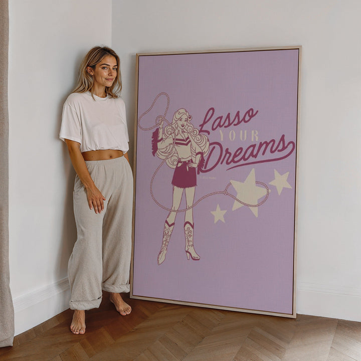 Woman standing next to artwork with 'Lasso Your Dreams' text and illustration.