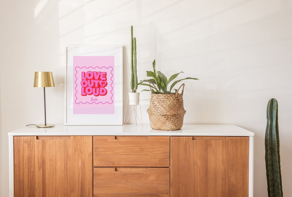 Wooden cabinet with a pink poster, lamp, and plants on a white wall.