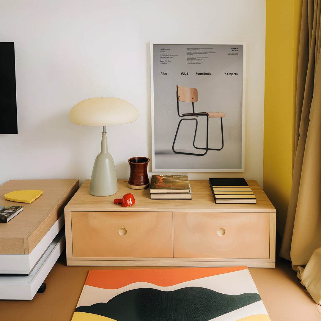 Modern room interior with wooden sideboard, lamp, books, and a picture of a chair.
