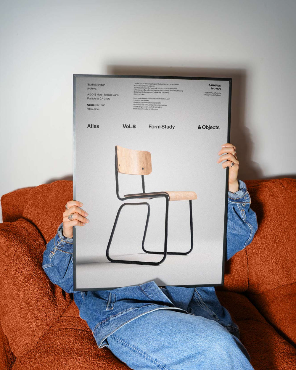 Person sitting on a couch holding a poster of a chair design.