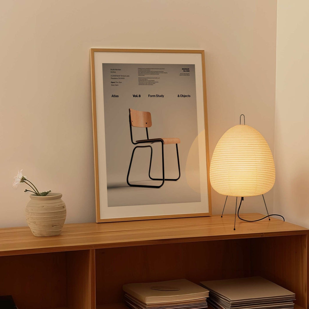 Wooden shelf with a poster of a chair, a lamp, and a vase against a beige wall.