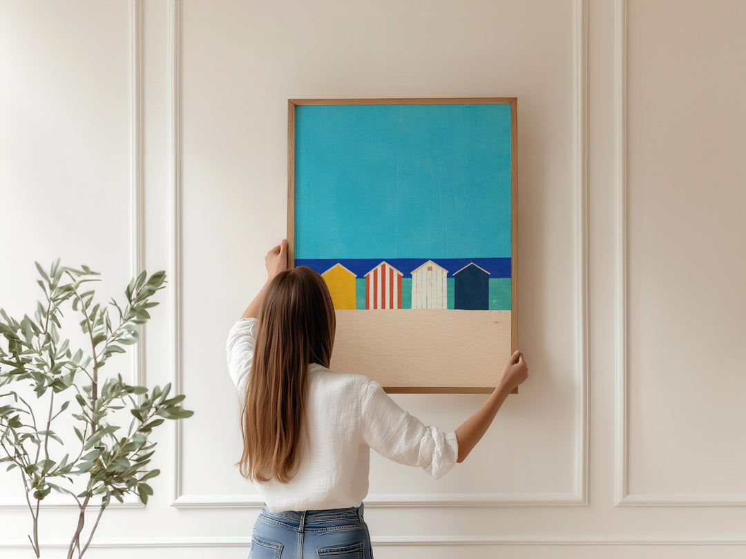 Woman hanging a colorful abstract painting on a wall