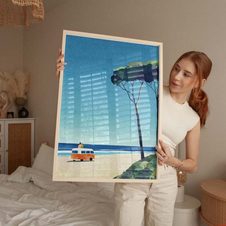 Woman holding an artwork of a scenic landscape with a tree, boat, and kite.