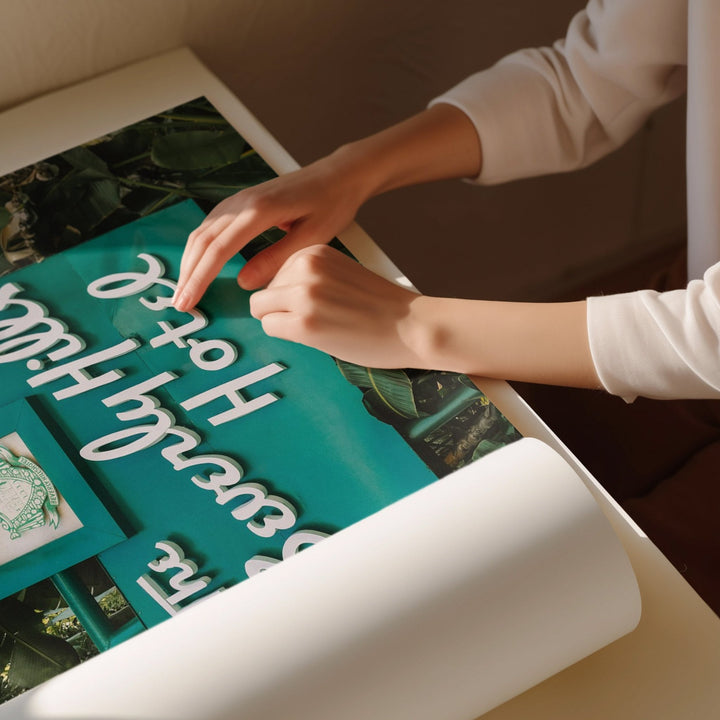Person arranging decorative letters on a green board with a blurred background