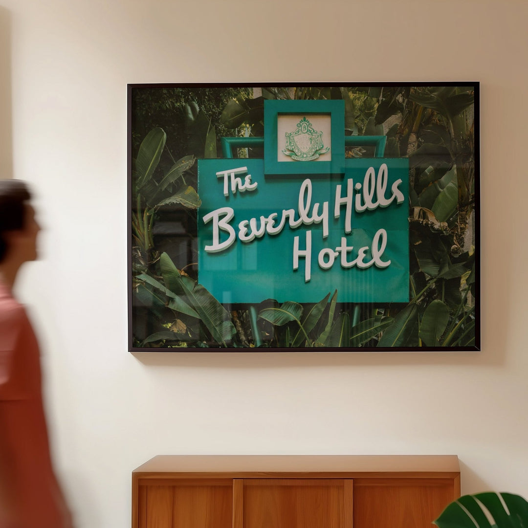 Person walking past a wall with 'The Beverly Hills Hotel' sign