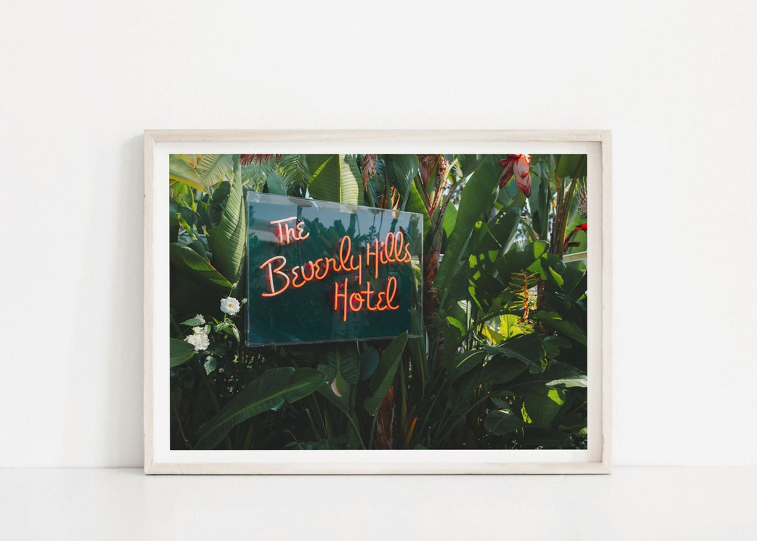 Photograph of a neon sign for 'The Beverly Hills Hotel' amidst greenery.