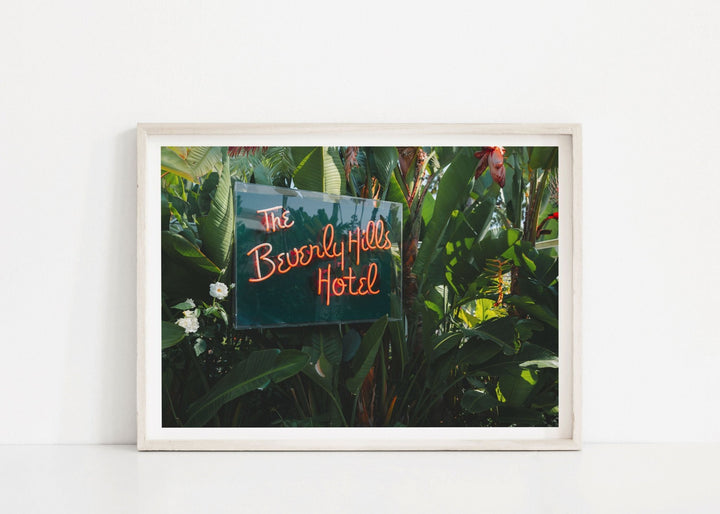 Photograph of a neon sign for 'The Beverly Hills Hotel' amidst greenery.