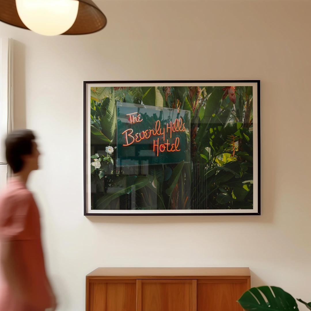 Picture of The Beverly Hills Hotel sign on a wall with a person walking by.