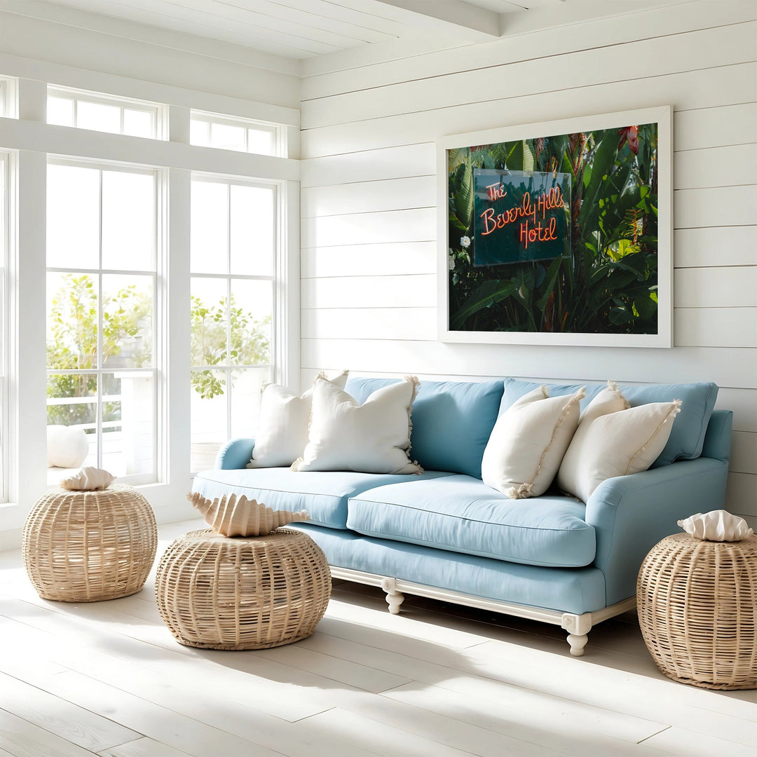 Light blue sofa with white pillows in a bright room with large windows and a picture on the wall.