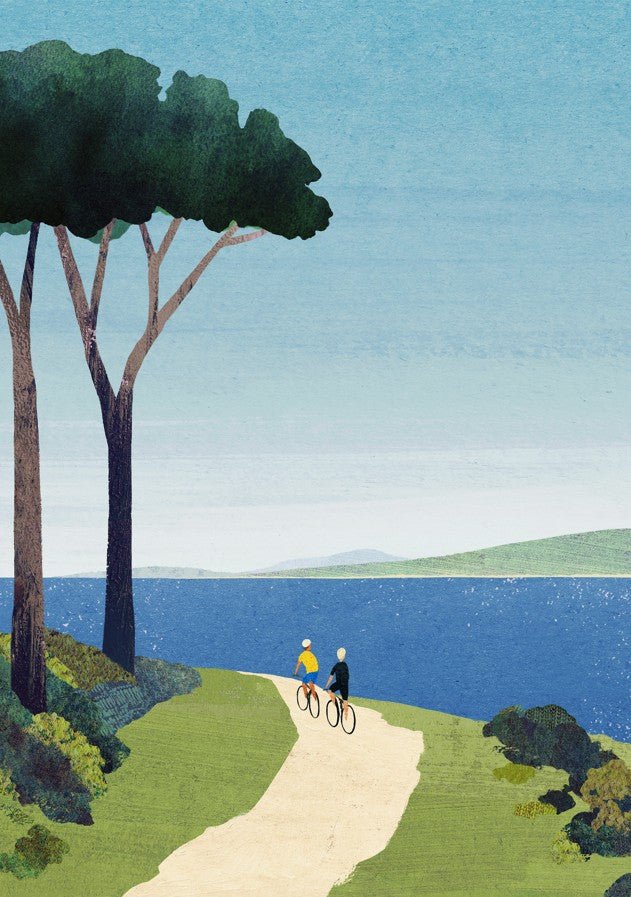 Two people riding bicycles along a path by a lake with trees in the background. framed