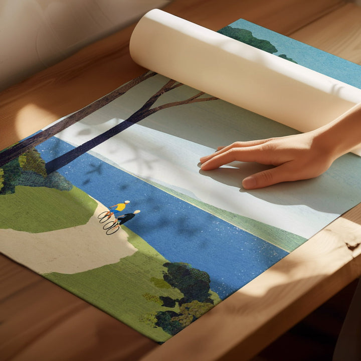 Person unrolling a scenic placemat with a landscape design on a wooden surface.