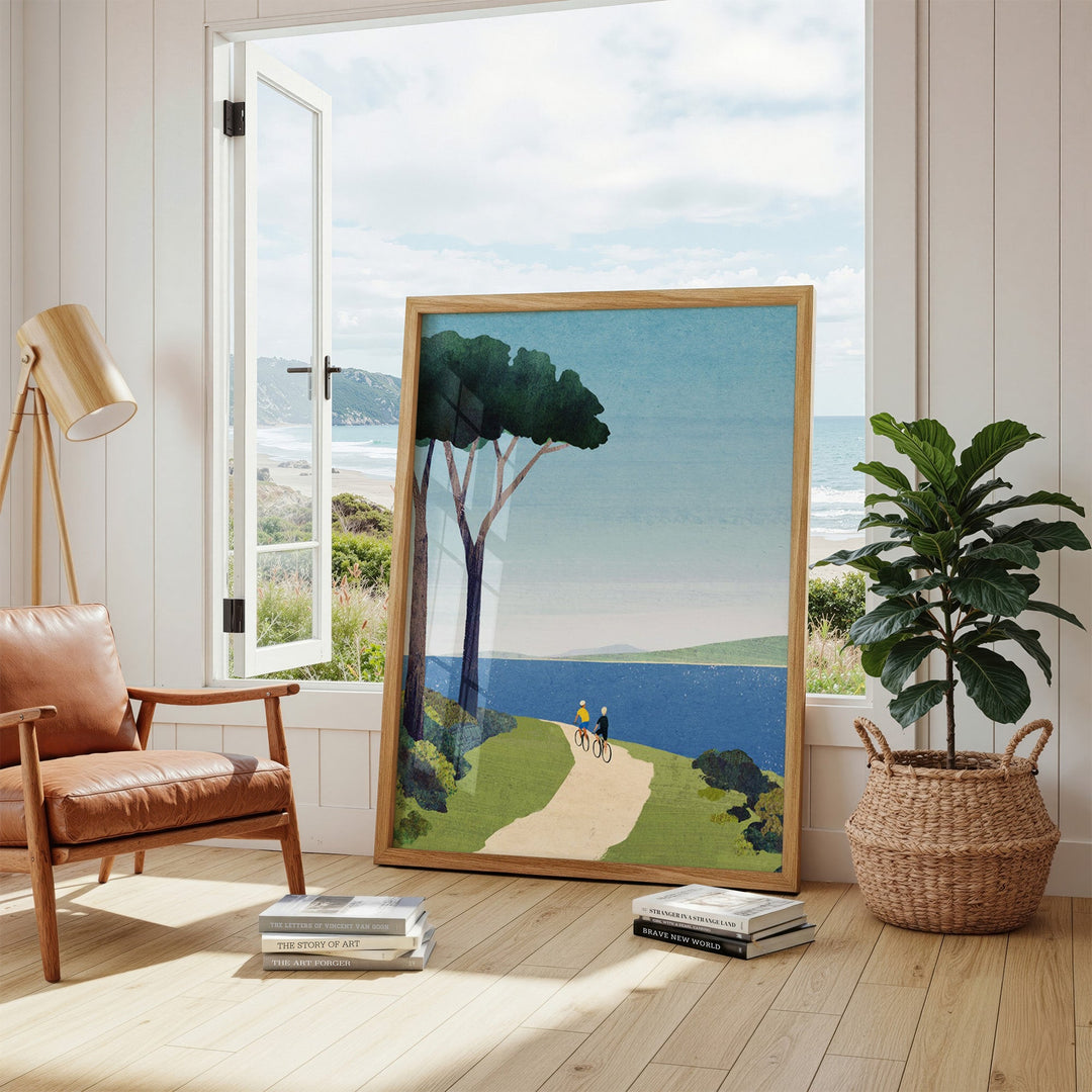 Artwork of a scenic landscape with trees and a path, placed in a room with a chair and plant.