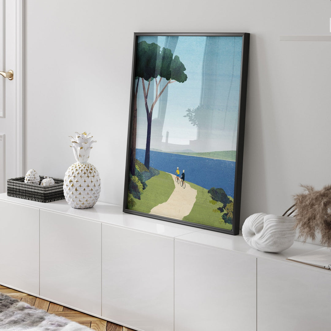 Artwork of a scenic landscape on a white wall above a white cabinet.