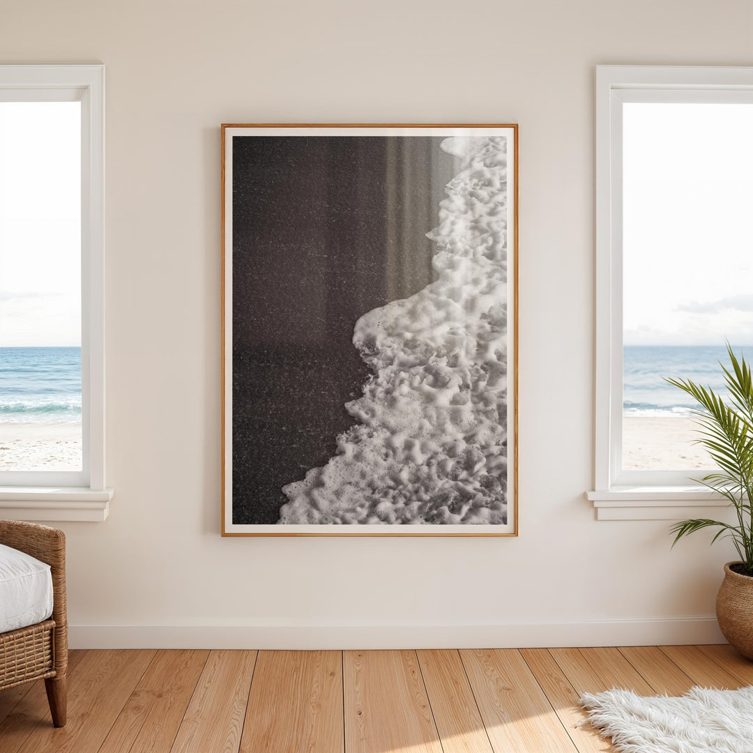 Abstract artwork on a wall with two windows showing a beach view.