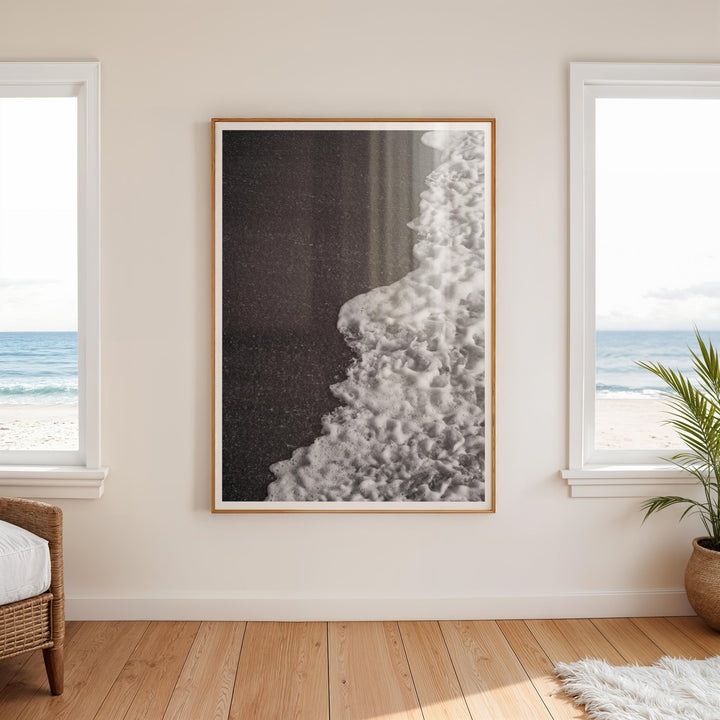 Abstract artwork on a wall with two windows showing a beach view.
