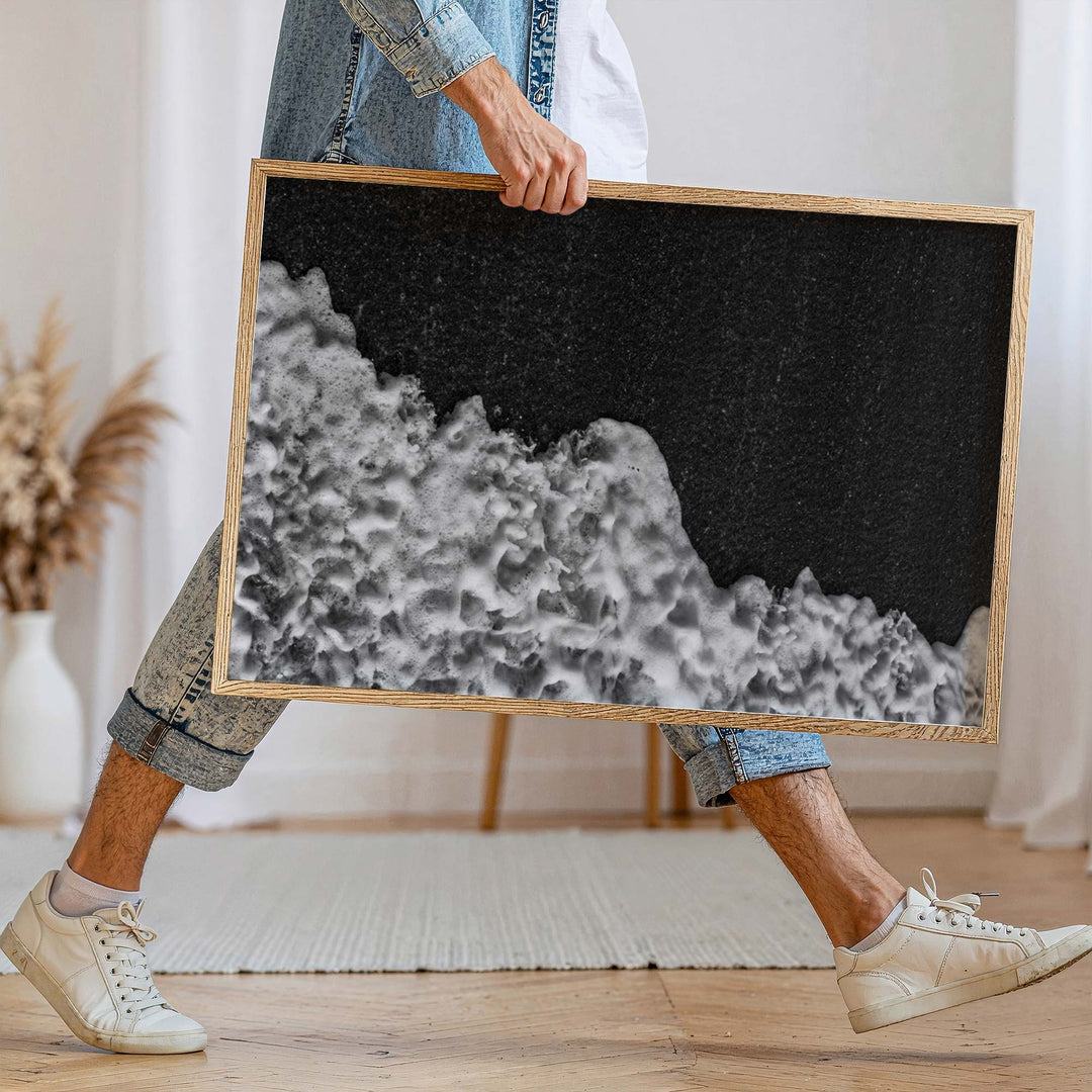 Person holding a black and white abstract artwork indoors.