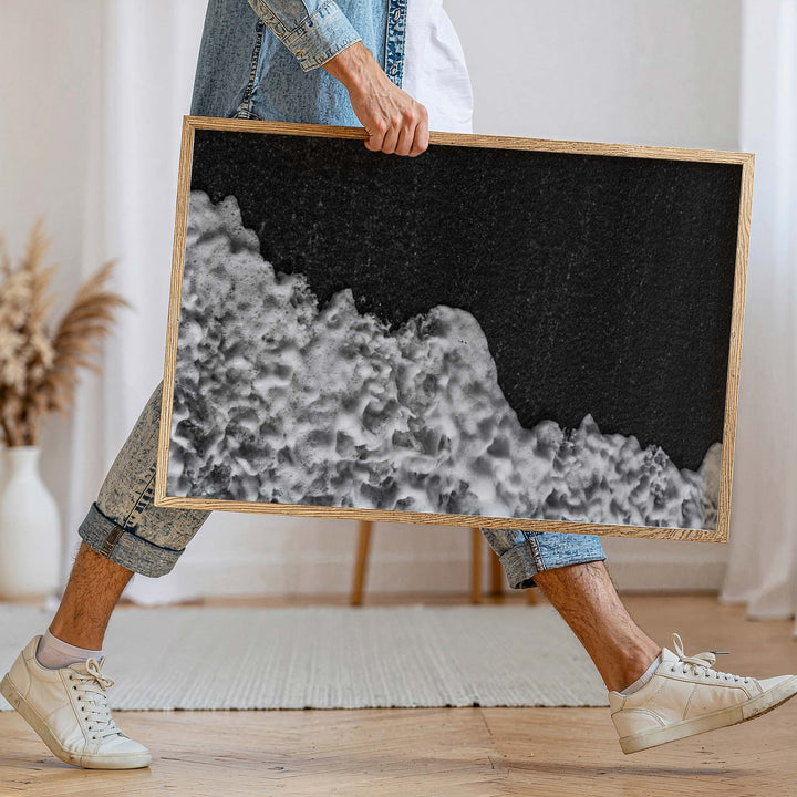 Person holding a black and white abstract artwork indoors.